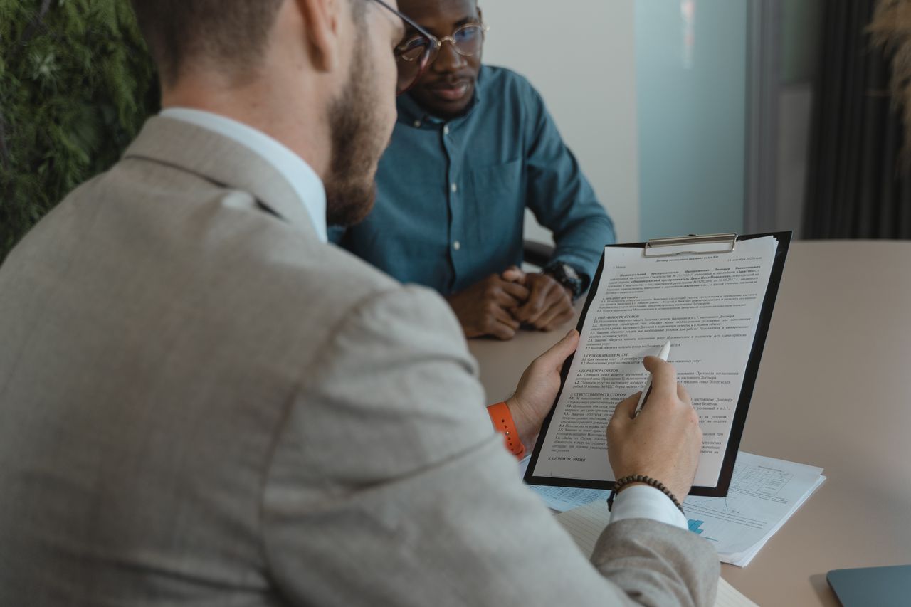 Job Postings A recruiter reviews a candidate's documents during a job interview in a modern office setting.
